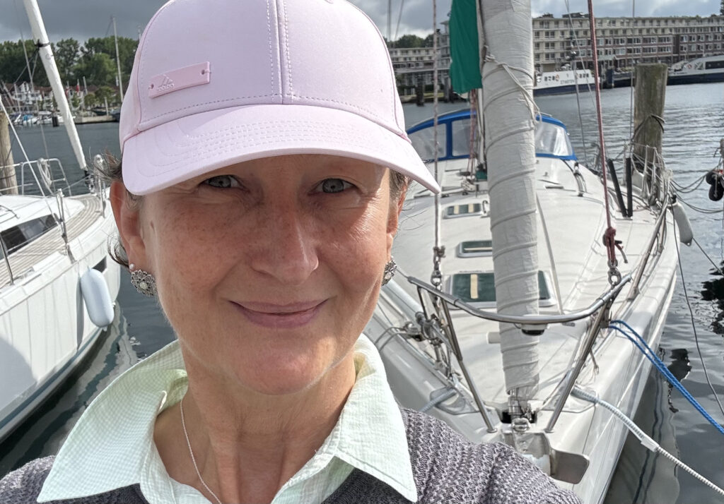 Portrait von Anke Roß mit Hafen im Hintergund und Cap auf.